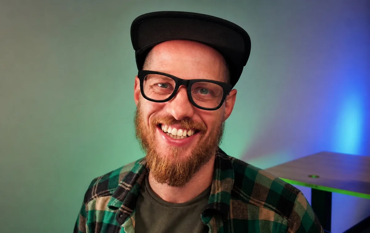 Kevin Kirchner, smiling, in a black cap, glasses and a green plaid shirt