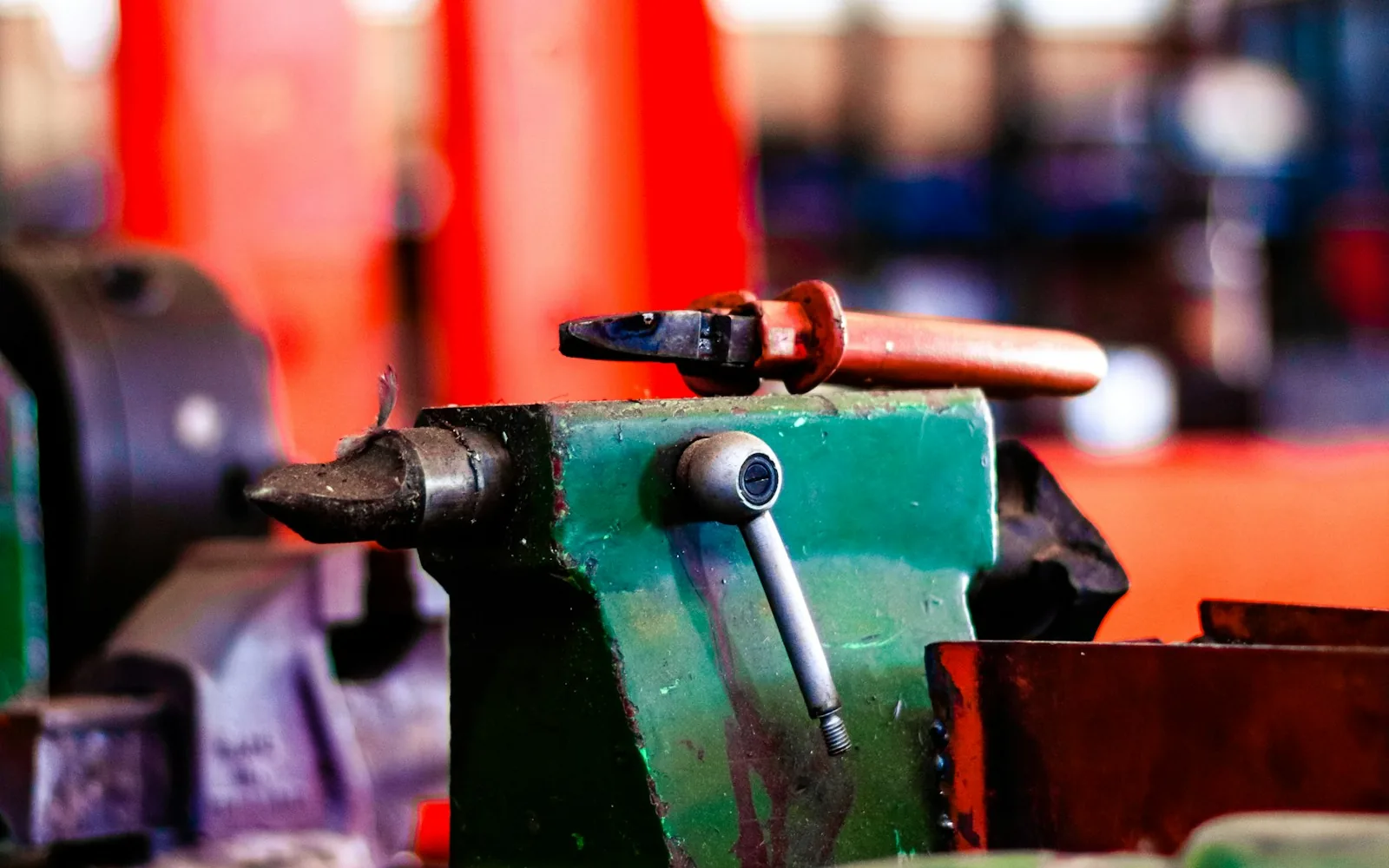 Close-up of a worn green lathe tailstock and tool holder in a busy shop