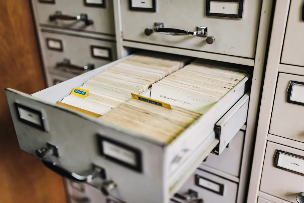 An open metal filing cabinet drawer packed with old paper records