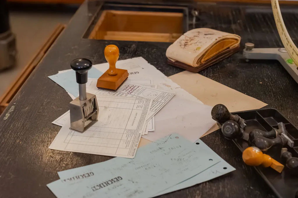 Inspection forms, a numbering stamp and rubber stamps scattered across a worn shop desk